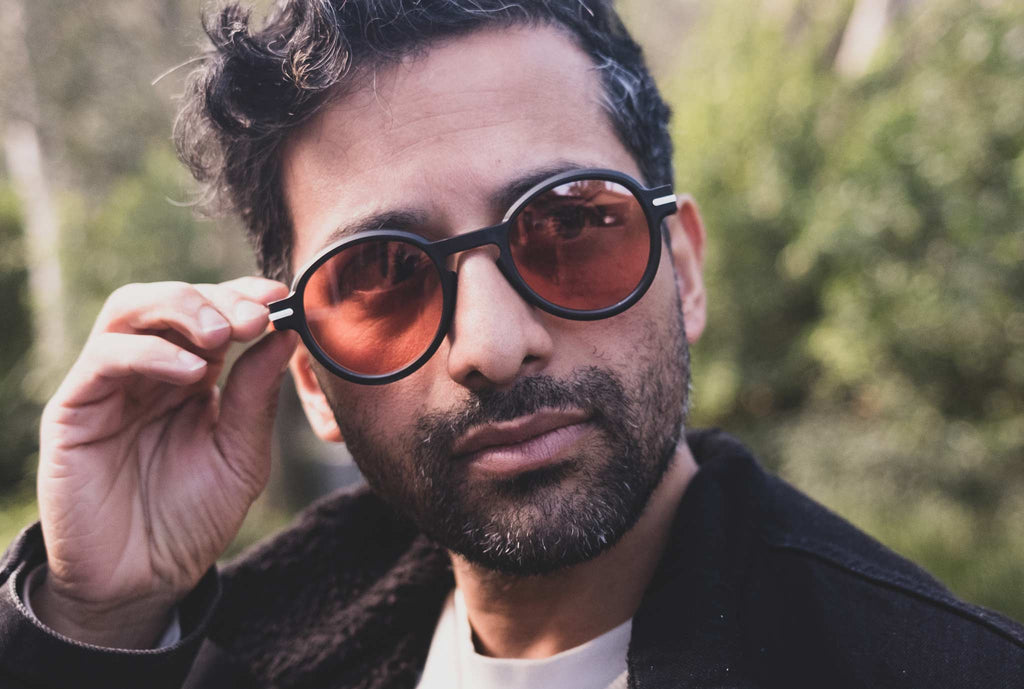 man wearing black round glasses with orange tint lenses outdoors