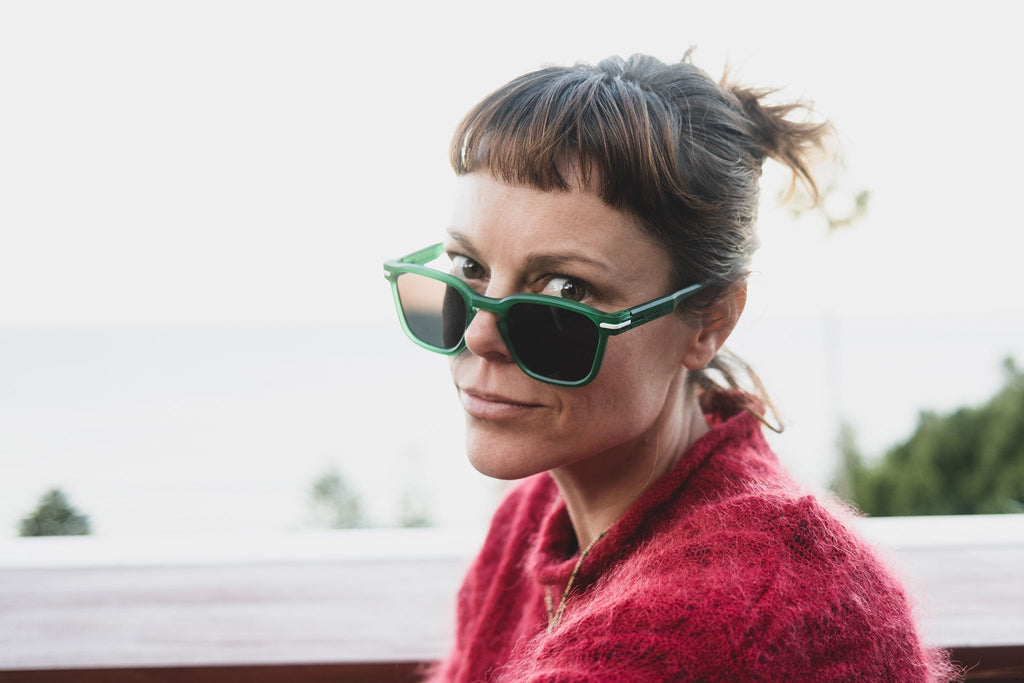 Woman peeping eyes over Good Citizens green sunglasses, made in Sydney from 100 percent recycled frames.