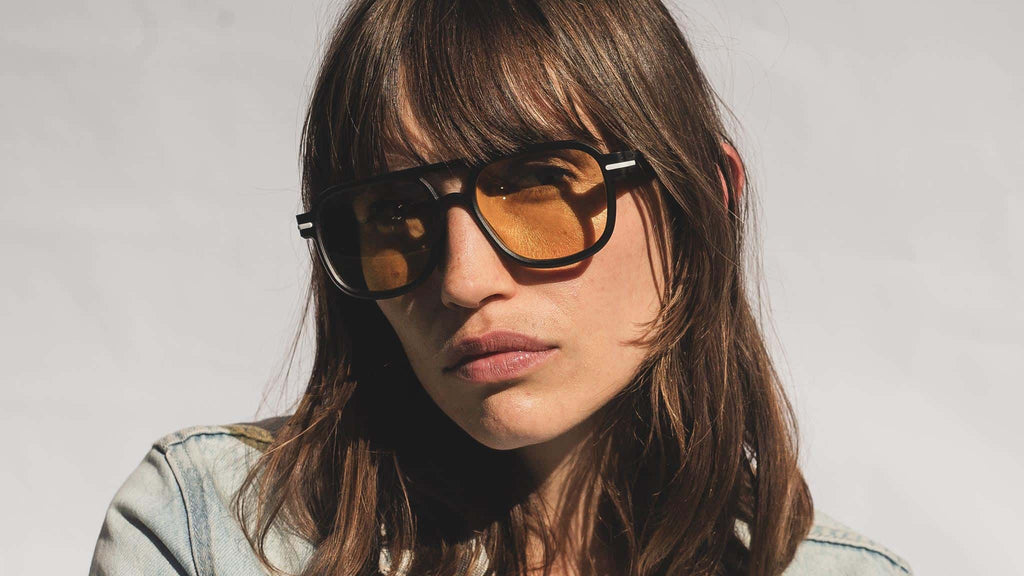 model wearing aviator sunglasses with yellow tinted lenses pulling a pose